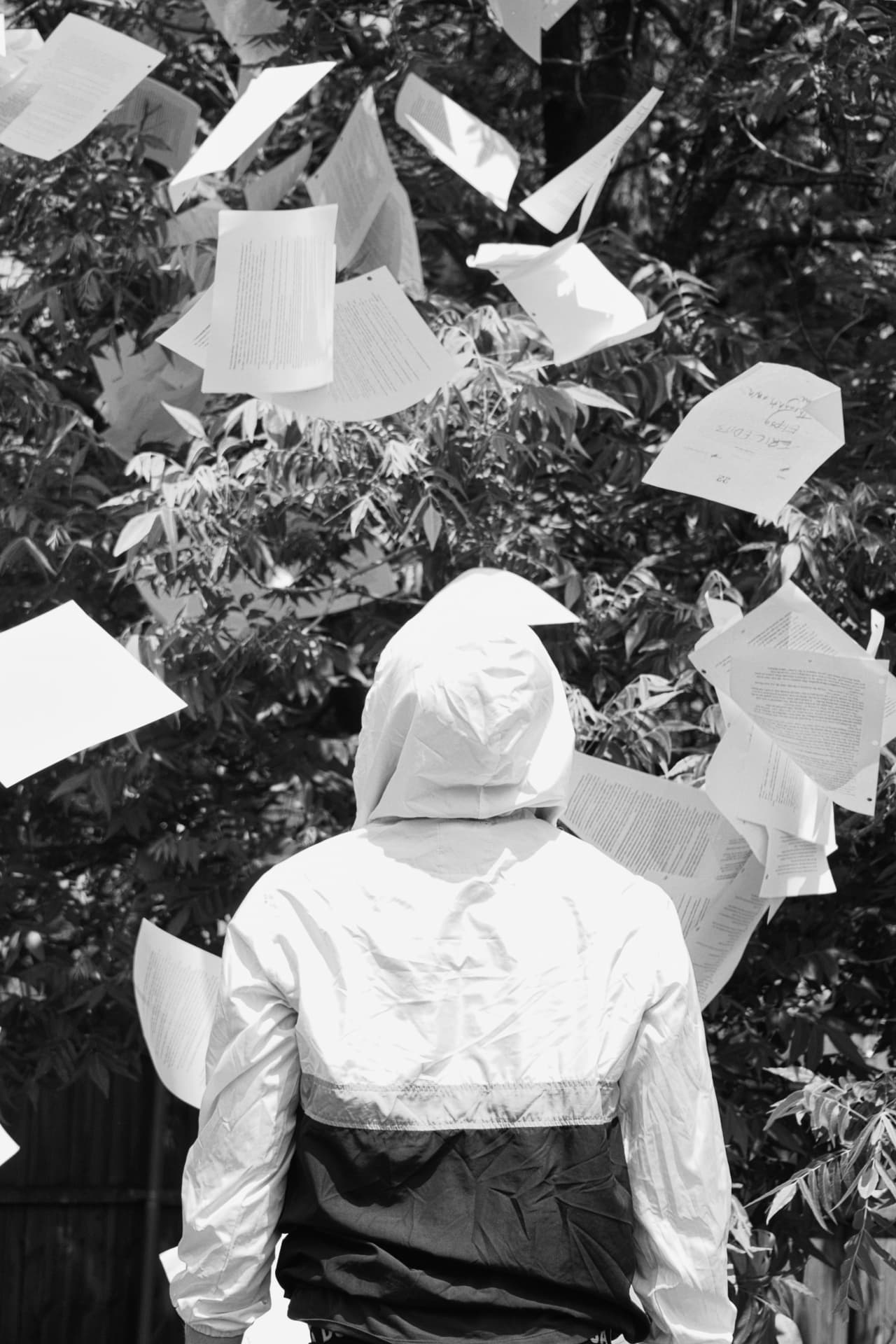 Loose manuscript pages falling through the air around a hooded figure